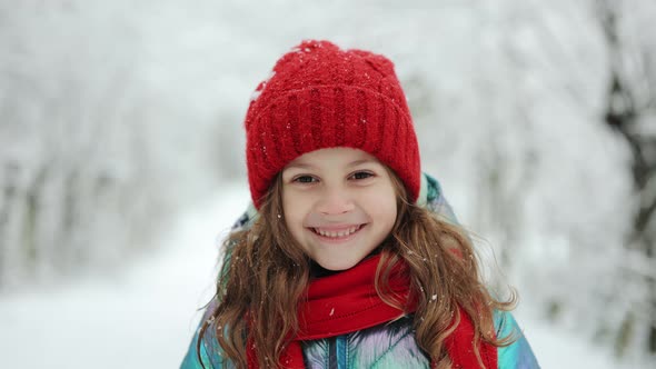 Close Up of Happy Cute Girl Looking at the Camera and Smiling the Background of a Snowy Forest