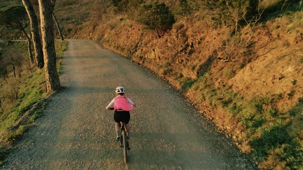 Drone Footage of Woman Cyclist in Sunset on Bike alt