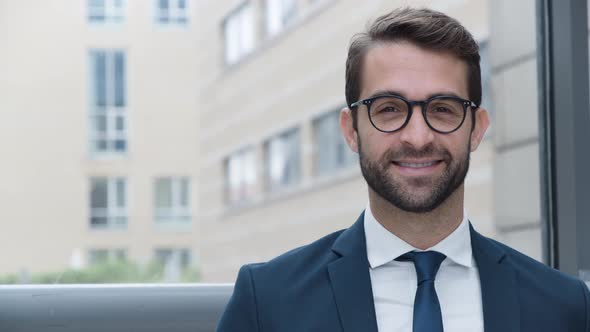 Businessman Adjusting Glasses Before Smiling