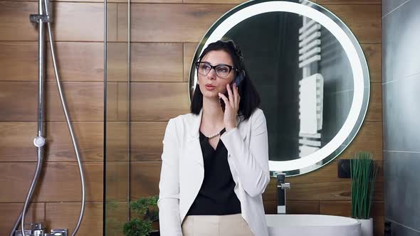 Modern Young Woman in White Suit which Has Phone Conversation in Her Bathroom alt
