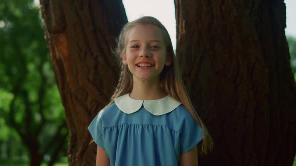 Joyful Little Girl Pose at Tree Trunk alt