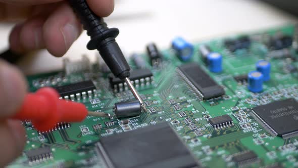 Computer Engineer with Tester Examining Motherboard alt