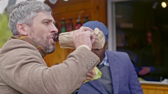 Two men drinking and eating outside food trailer