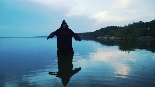 Scary figure in black mantle in the river alt
