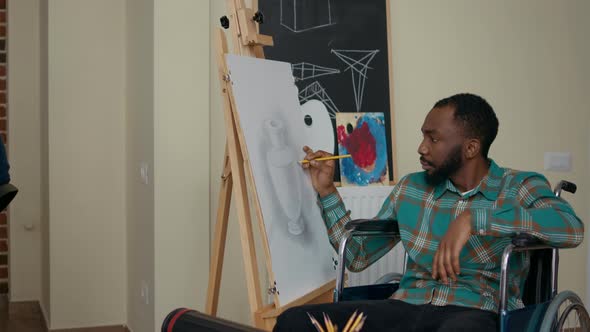 African American Man with Disability Using Pencil to Draw on Canvas alt