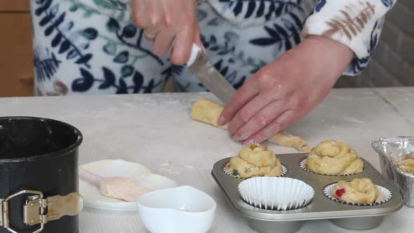 A Woman Cuts A Roll Of Rolled Dough. Prepares Cruffin With Raisins And Candied Fruit. alt