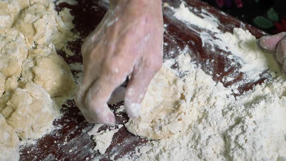 Wrinkled Hands of an Elderly Man Knead the Dough and Make Balls of Kolobok alt