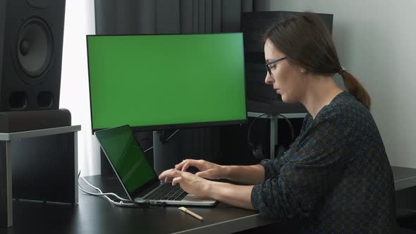 Female employee working on laptop computer from home workplace green screen. alt