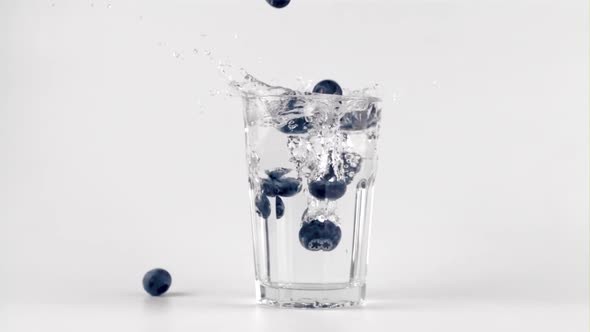 Super Slow Motion of the Blueberries Falls Into a Glass of Water with Splashes alt