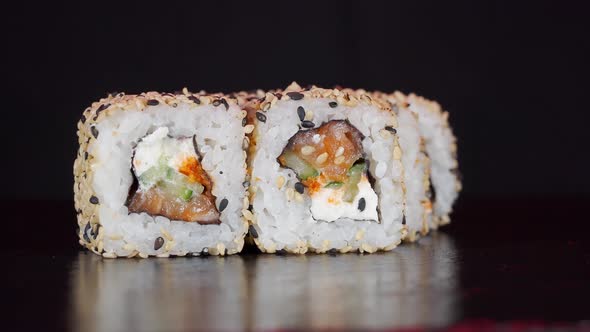 Sushi Rolls Rotate on Black Background. Close-up Shoot. Philadelphia Cheese and Salmon in Japanese