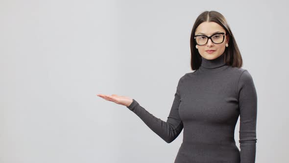 Woman In Gray Turtle Neck DressMaking Presentation Gesture, Copy Space On A Left Side