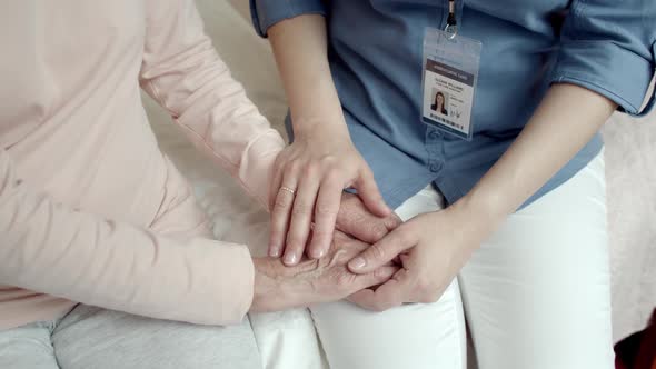 Close up of Home Nurse Stroking Hands of Senior Woman Patient.