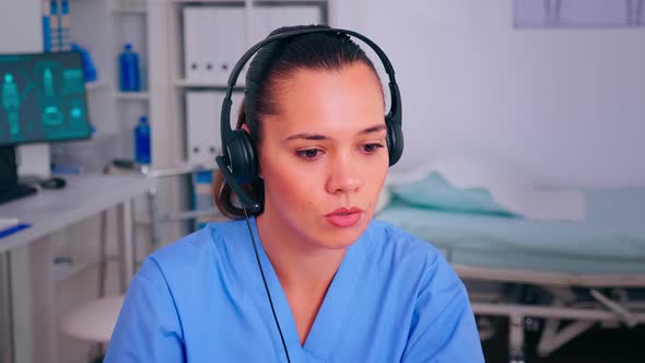 Specialist Nurse Answering Using Headphones Checking Appointment During Telehealth alt