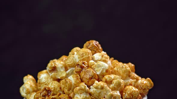 Coffee taste popcorns rotating into the bowl on black background close up. Caramel popcorn. Health alt