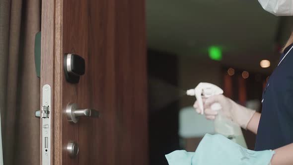 Housekeeper with protective mask disinfecting door handle