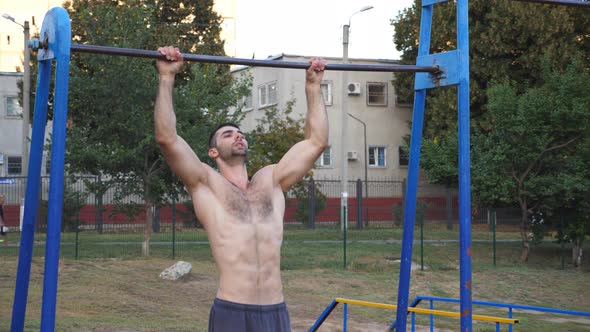 Young Sportsman Doing Pull Ups at Sports Ground alt