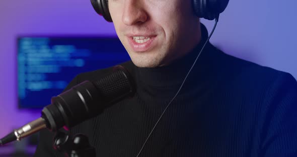Closeup of Male Blogger in Headphones Talking in Microphone Recording Podcast in Studio alt