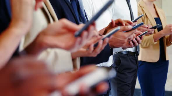 Business executives using mobile phone alt