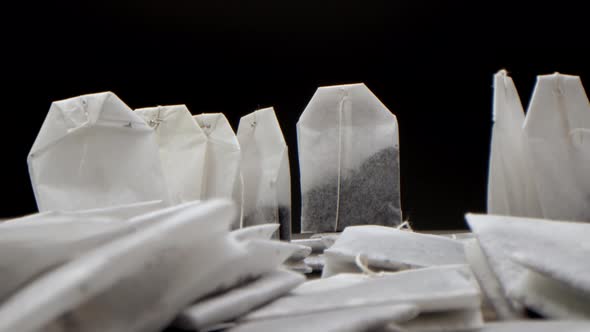 Super Closeup Set of Tea Bags on a White Table on a Black Background is a White Cup of Tea alt