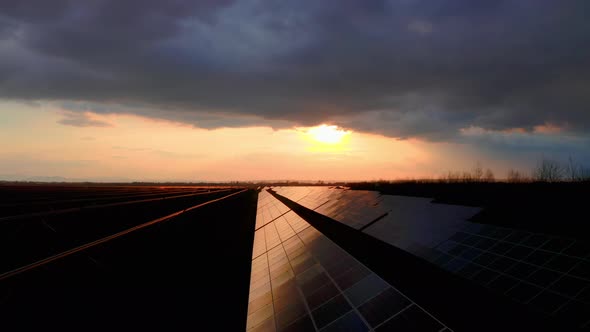 Flyover Solar panels Power plant at Sunrise. Storm Clouds above Solar Panel Farm. alt
