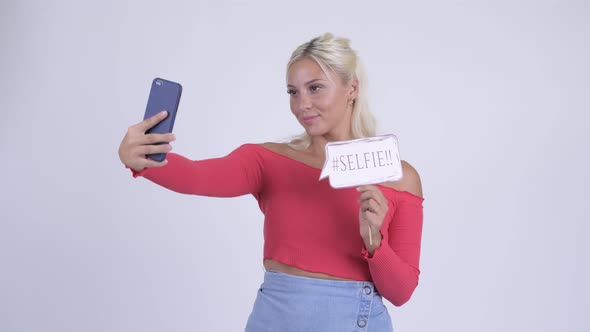 Happy Young Beautiful Blonde Woman Taking Selfie with Paper Sign alt