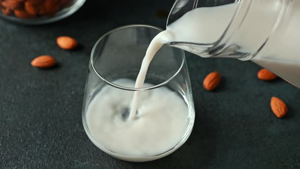 Pouring almond milk in glass. Vegan milk. Plant based milk replacer and lactose free