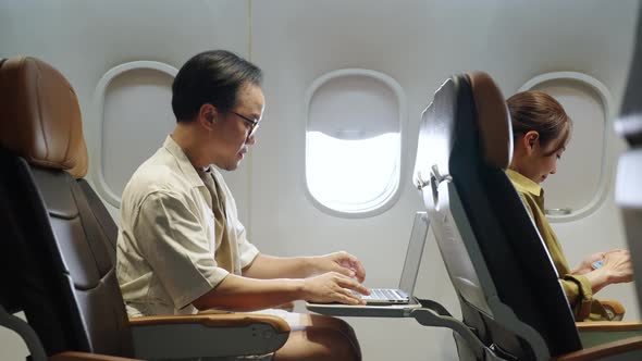 4K Asian businessman working on laptop computer while travel on airplane.