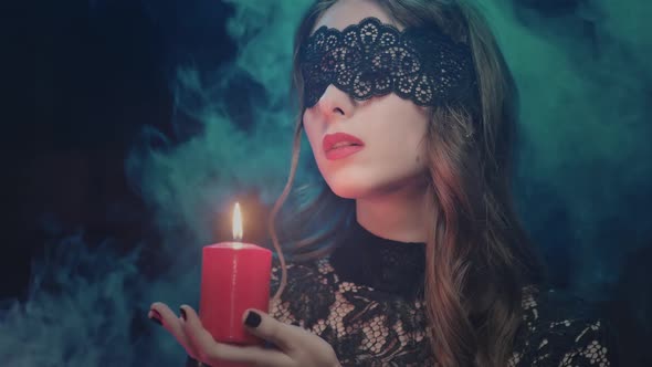 Mystical Female in Black Attire with Red Candle Looking at the Camera Halloween Feast of All Saints