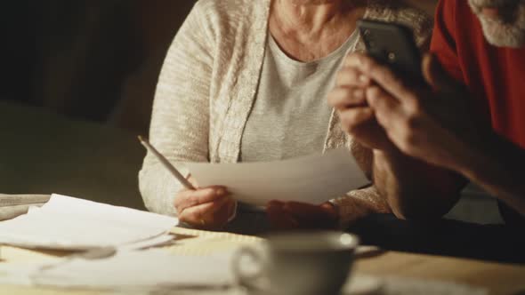 Elderly Couple Calculating Utility Payments and Joking alt
