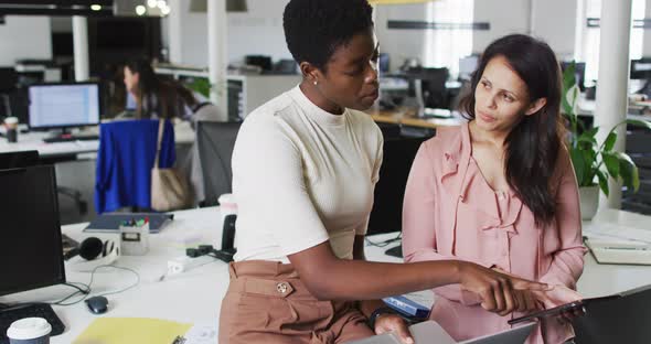 Focused diverse businesswomen working together on laptop in office alt