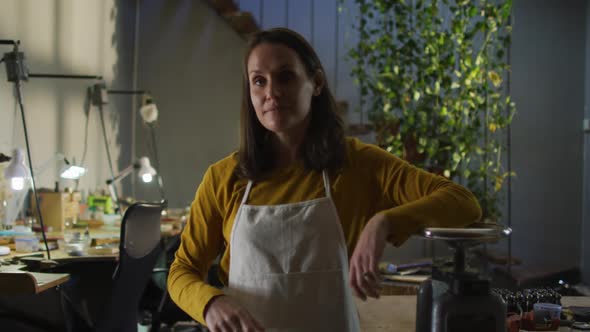 Portrait of caucasian female jeweller in workshop wearing apron smiling to camera alt