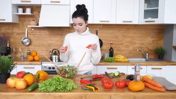 Young Woman Cooking Healthy Salad For Dinner On Her Kitchen. alt