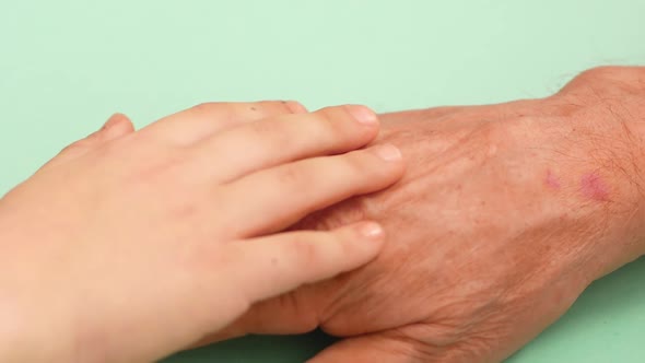 Friendship and support for grandson and grandfather theme. Close-up of a kid's hand stroking his gra alt