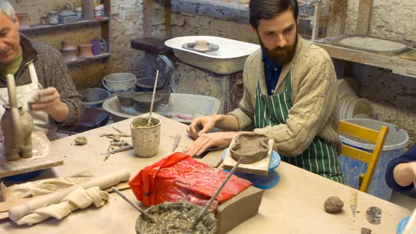 Potter and colleagues working on clay sculpture alt