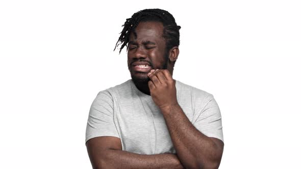 Portrait of Unhealthy African American Man in Basic Tshirt Suffering From Toothache and Touching alt