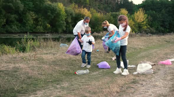 A family of volunteers with children clears the river Bank of garbage