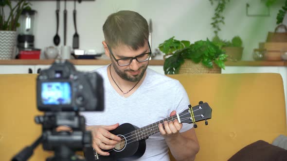 Blogger Records Video on Camera Playing Guitar