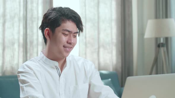 Close Up Of A Happy Asian Man Student Typing On Computer At Home alt