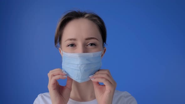 Slow Motion: Woman Putting on Medical Face Mask and Looking at Camera - Close Up
