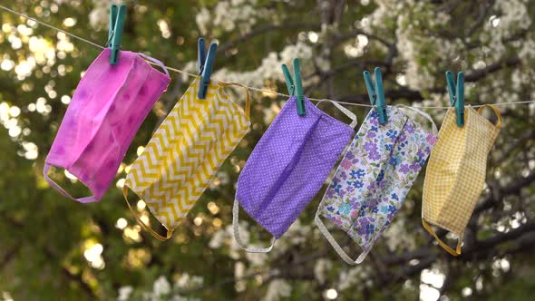 A reusable DIY fabric cotton mask is dried on a clothesline in the open air for reuse alt