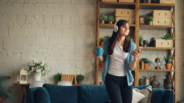 Young Brunette Is Listening To Music Through Headphones and Using Smartphone Looking at Screen alt