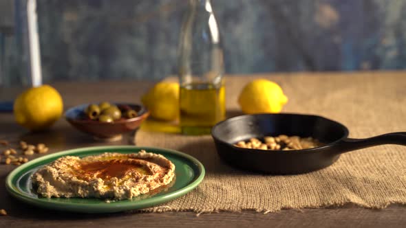 Warm, low angle slide to the right showing middle eastern food spread of olives, pine nuts, hummus, alt