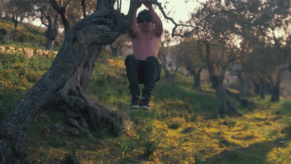 Young strong lean fit man does tucked knee raise pull ups alt