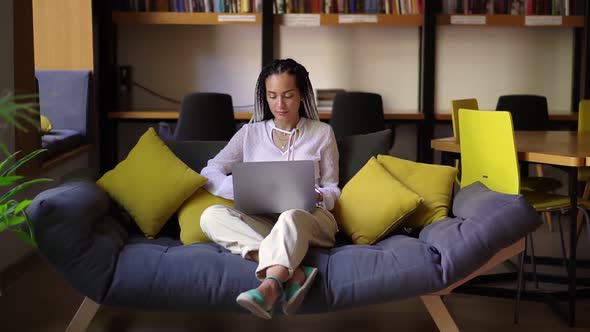 Stylish Young Woman with Dreads Working on Laptop at Home Office or Public Workplace alt