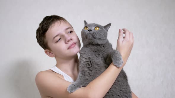 Smiling Child is Holding Hugging Kisses a Fluffy Cat in Her Arms in Room alt