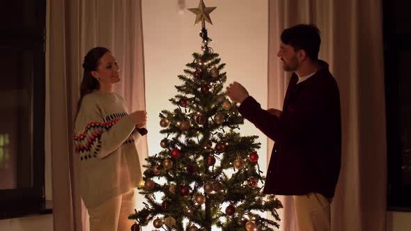 Happy Couple Decorating Christmas Tree at Home