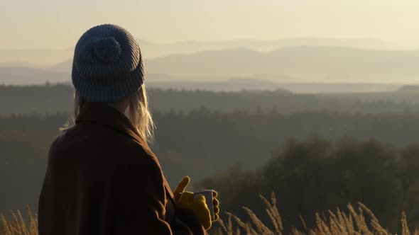 woman hold mug of tea in mountains Sudetes in November in sunset