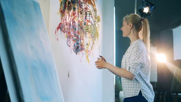 Blond Lady is Cheerfully Painting an Abstract Picture alt