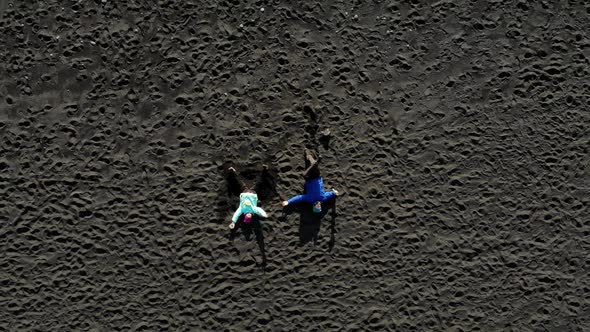 Two People Lies on the Black Sand of a Beach. Atlantic Ocean in Iceland.