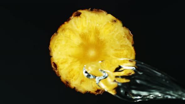Super Slow Motion Shot of Splashing Water on Rotating Pineapple Slice at 1000Fps. alt